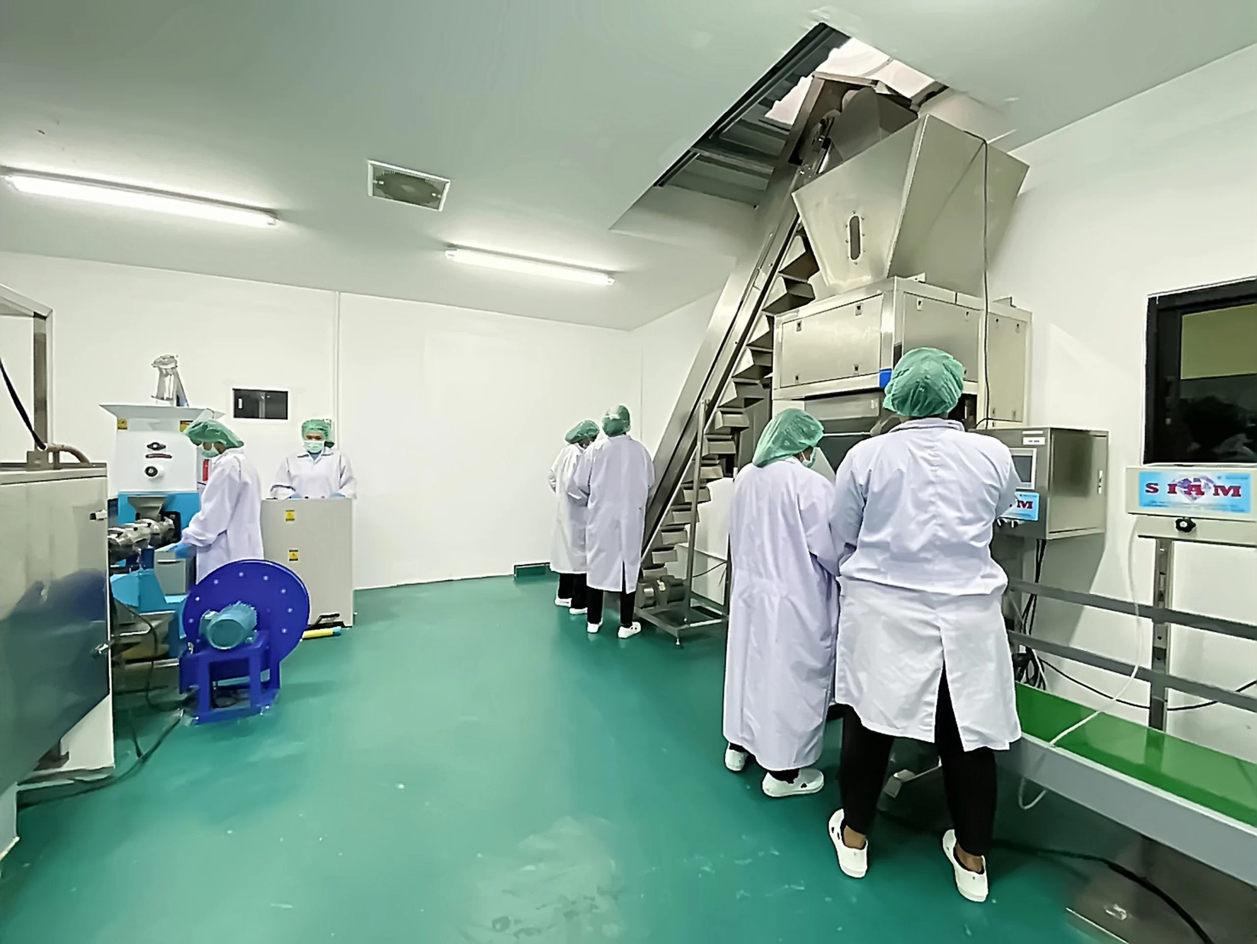 ภาพภายในโรงงานผลิตอาหารสัตว์เลี้ยงที่มีเครื่องจักรและพนักงานกำลังทำงาน